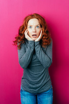Young surprised woman on pink background