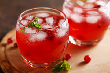 Two glasses of summer cold drink with cranberry juice, mint, ice cubes on the table.