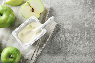 Plastic cup with yummy apple yogurt on table