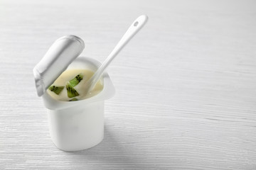 Plastic cup with yummy kiwi yogurt on wooden table
