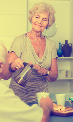 Happy senior woman pouring tea