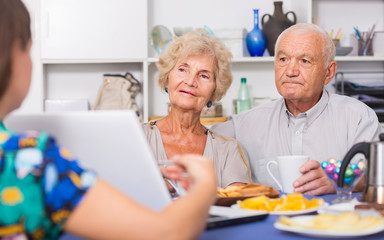 Fototapeta na wymiar Young woman showing elderly couple something on laptop
