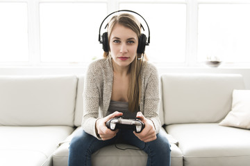 Beautiful young woman sitting on sofa with game controller