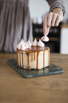Close up of woman's hand decorating caramel cake