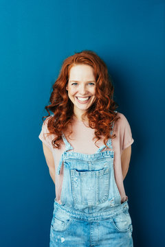 Happy cheerful young redhead woman in dungarees