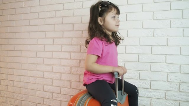 The child is leaving. The child on the suitcase leaves.