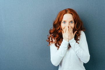 Excited young redhead woman staring at camera