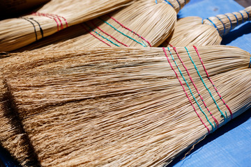 weaving brooms at market