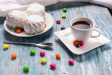 Cup of coffee and colored candies on blue table