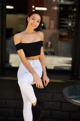 Beautiful sporty girl standing near the wall and pose to camera, spring time photo shoot