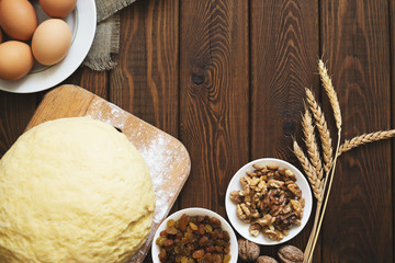 Bakery background, baking cake ingredients : eggs, flour, walnuts and raisins on wood table, top view