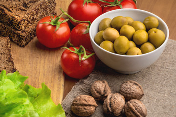 Ingredients for vegetarian sandwiches with healthy rye bread, tomatoes, green olives and lettuce on table. Healthy food