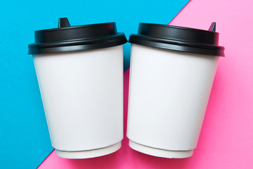Two disposable cups for hot drinks on a pink and blue geometric backgrounds. Trend colors.