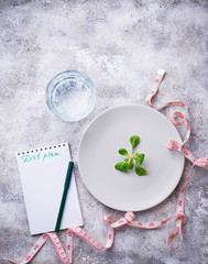 Plate with salad leaves, water and measuring tape