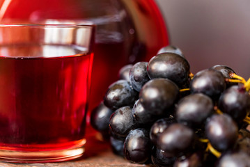 Red grape juice in glass and grapes close
