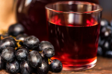 Red grape juice in glass and grapes close