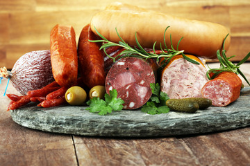 Food tray with delicious salami, ham,  fresh sausages, cucumber and herbs. Meat platter