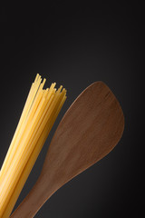 Nudeln Spagetti und Kochlöffel  dunkler Hintergrund