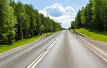 Fototapeta premium asphalt road through the forest in summer day at speed