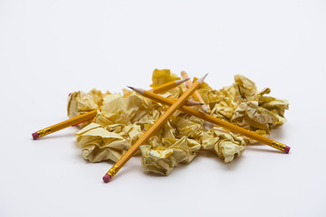 Yellow school pencils with crumpled yellow papers on white 