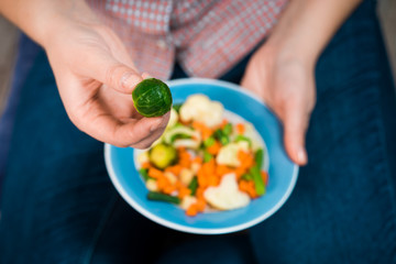 Girl with a plate of vegetables in hands. Healthy eating concept. Girl in jeans and a red shirt in a cage. Casual Style. Proper nutrition. Diet. Health. Vegetarian food. Vegans food.