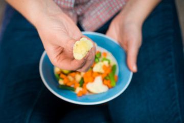 Girl with a plate of vegetables in hands. Healthy eating concept. Girl in jeans and a red shirt in a cage. Casual Style. Proper nutrition. Diet. Health. Vegetarian food. Vegans food.