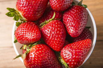 White bowl with some strawberries on a wooden table