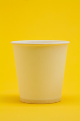 White paper cup on yellow background 