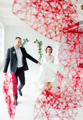 Bride and groom standing on white wall background