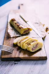 Roll made with smashed potatoes cheese and mortadella, on a wooden cutboard