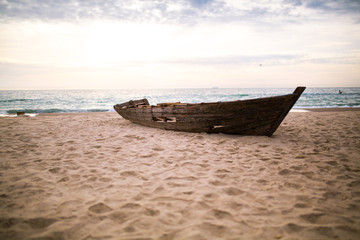 ￼ old wooden boat on a clean beach near the ocean ￼