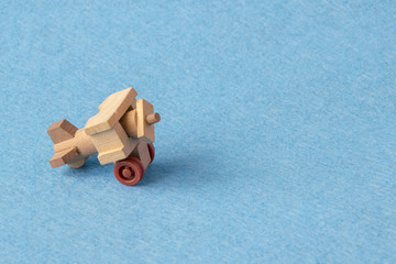 A wooden model of an old airplane on a blue background. Macro photograph of toy airplane.