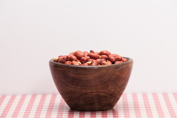  Peanuts in wooden bowl on a background of red and white checkered table 