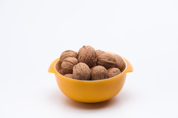 Yellow bowl full of walnuts isolated