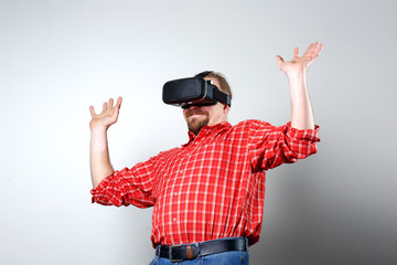 Portrait of bearded man watching virtual reality glasses over gray background with copyspace.