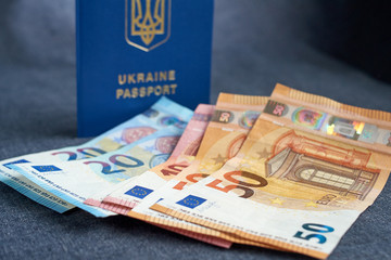 Ukraine passport with Euro Bills inside. On a gray backgraund
