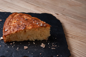 Apple pie tart on shale board with raisins, nuts and cinnamon is a vintage wooden background texture. Rustic style