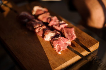 Skewers with stringed pieces of fresh meat arranged on the fooden desk