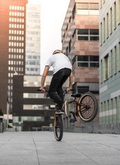 Young rider making trick on bmx bicycle in the street.