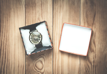 Wrist watch in box on the wood background.