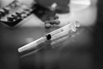 Cocaine divided into paths and syringe on a glass background