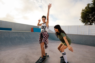 Female friends skateboarding together at skate park © Jacob Lund