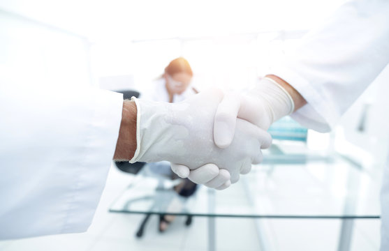 Doctors in lab coats greeting each other with handshake