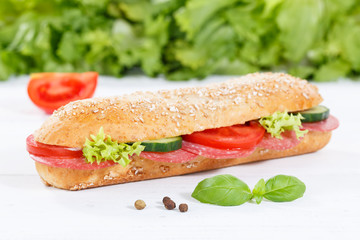 Sub sandwich whole grain grains baguette with salami ham on wooden board