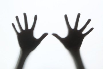 Hands silhouette behind a glass