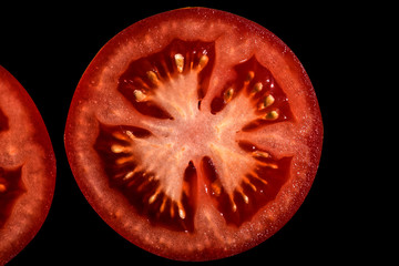 Sliced tomato isolated on black background. Texture tomato pulp. Red flesh and yellow seeds.