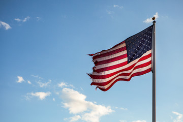 Fototapeta premium American flag blowing in the wind on the blue sky