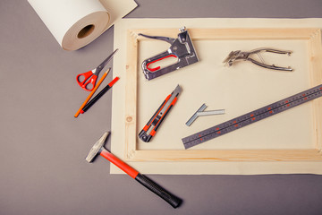 Canvas artist on roll, stretcher for canvas, staple gun and other tools on a gray background