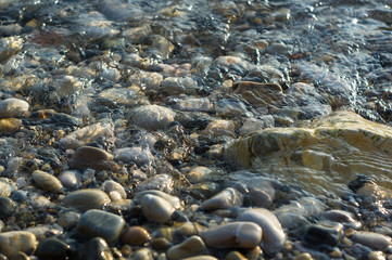 pebble stones on the sea beach, the rolling waves of the sea with foam