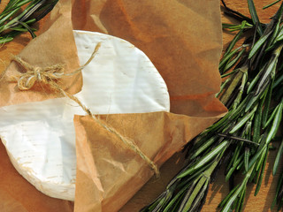 Camembert cheese in paper, fresh rosemary